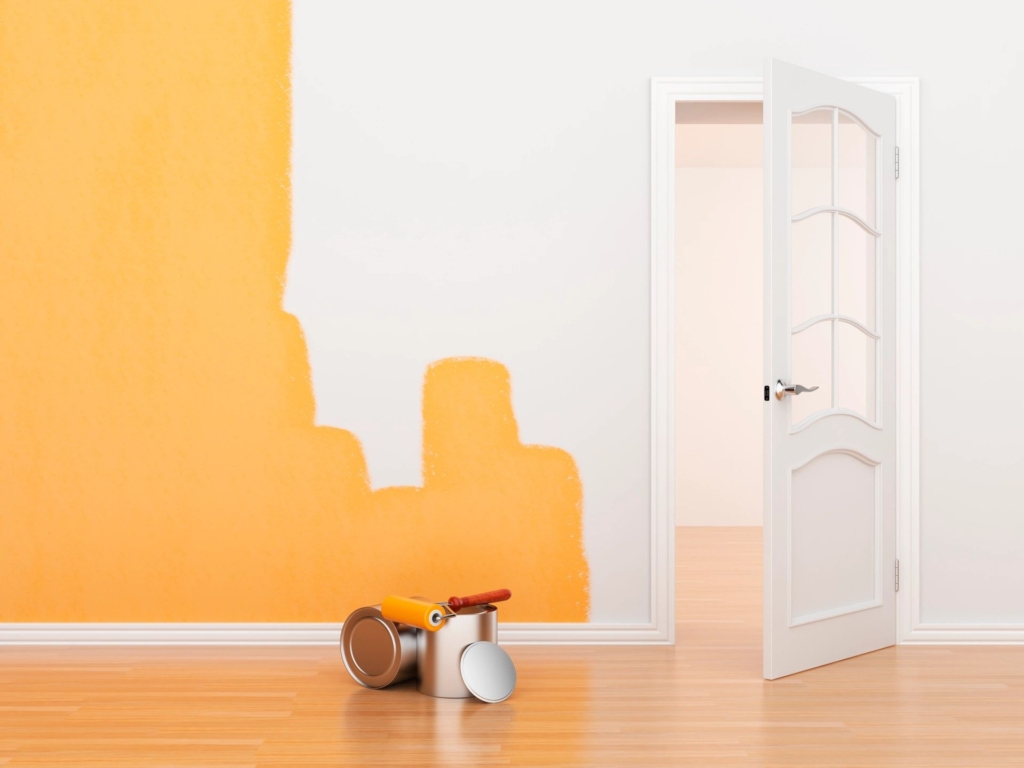 Paint on a wall with the paint cans on the floor next to an open door